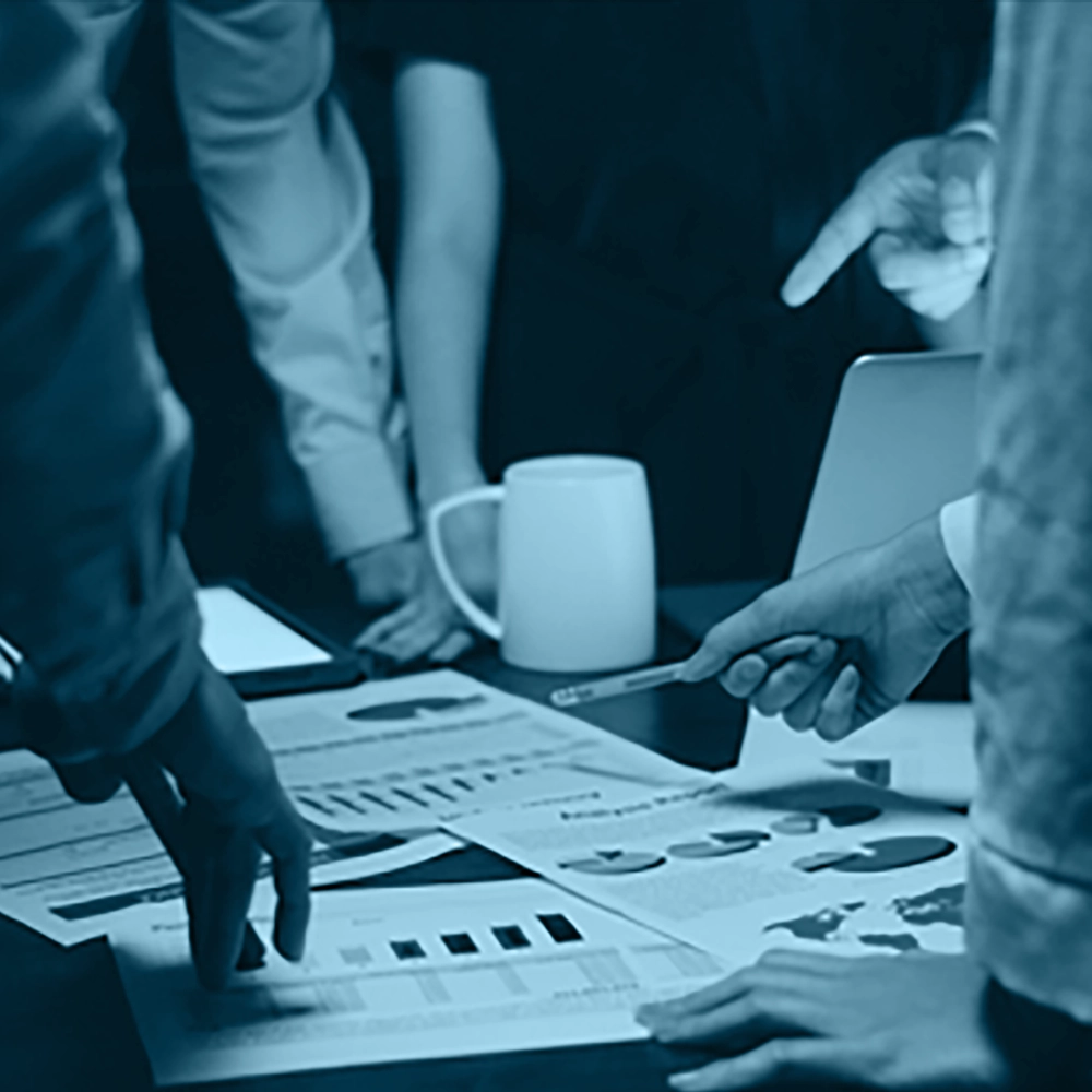 Group of employees discussing reports with charts on a table, related to compliance and GRC.