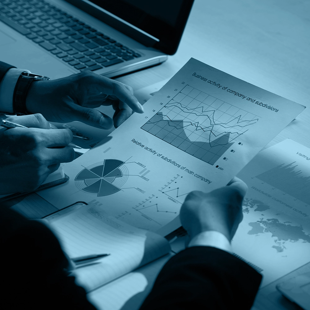 Employees discussing a plan and reports on a table related to third-party risk monitoring.